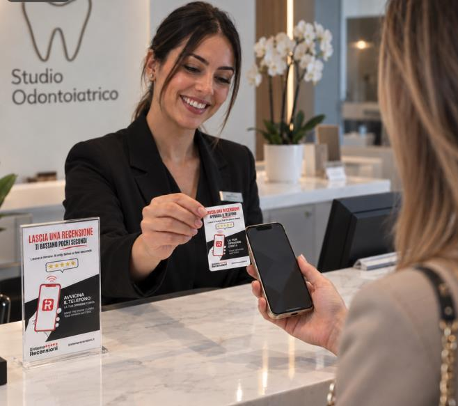 Alla reception di uno studio odontoiatrico, una collaboratrice avvicina una card NFC al telefono di una paziente